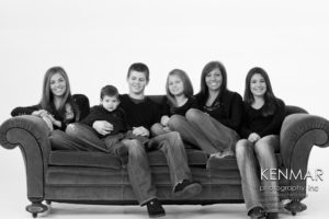 Family siblings posing on a couch in a studio
