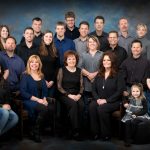 A professionaly posed family of 23 in black, blue and grey displayed as an example of KenMar's family category. 