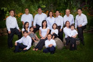 Family of 15 in white shirts and jeans in a garden setting