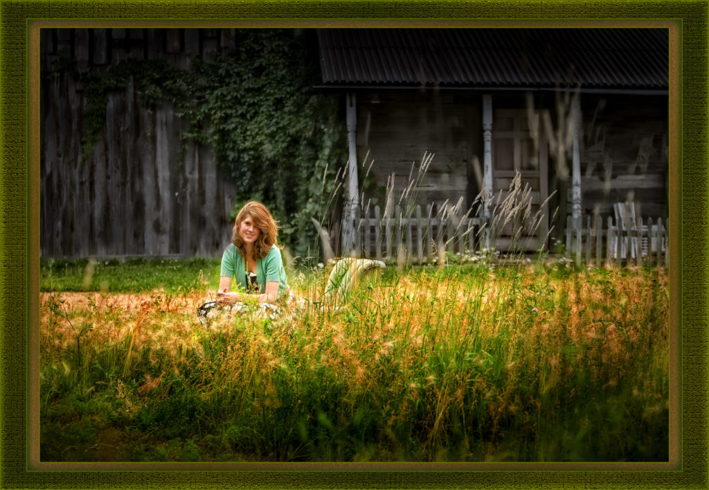 High school senior girl photographed in a field of tall grasses in front of an abandoned looking building. At 1120 N Hickory Farm Ln, KenMar's private photo park. 