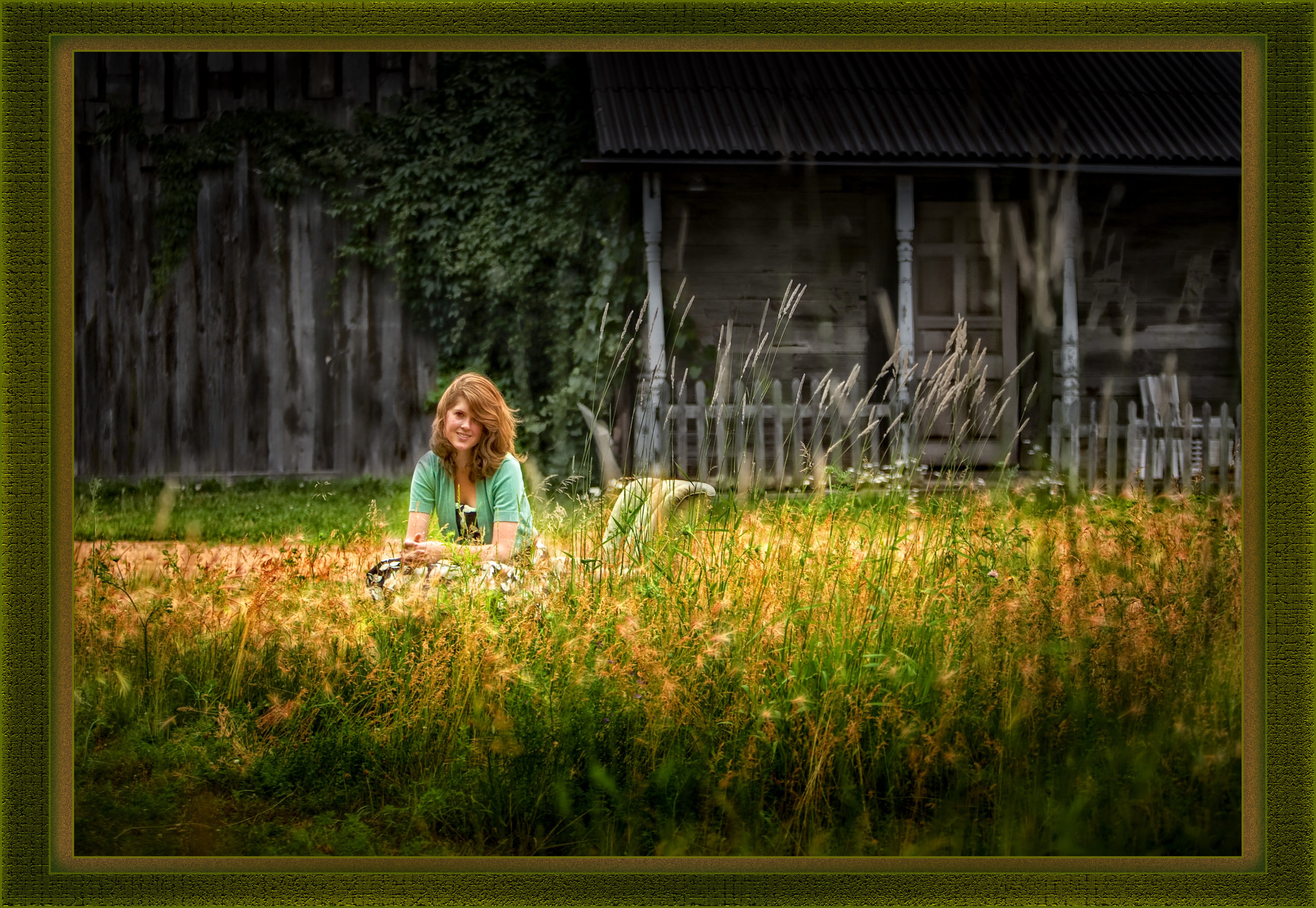 High school senior girl photographed in a field of tall grasses in front of an abandoned looking building. At 1120 N Hickory Farm Ln, KenMar's private photo park.